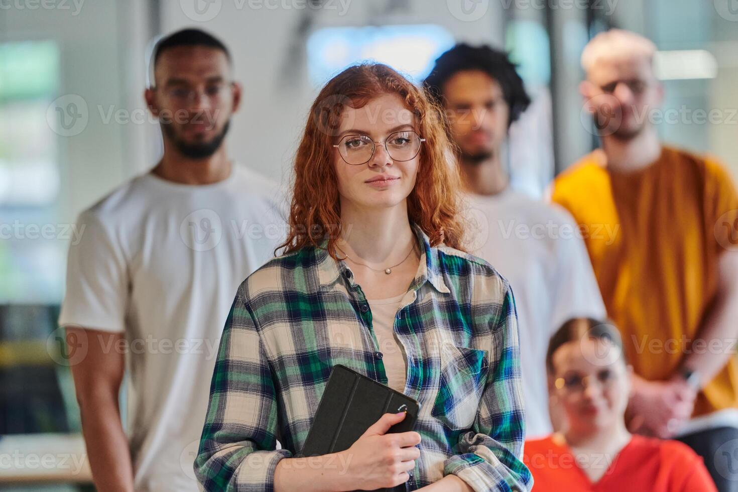 A diverse group of business people walking a corridor in the glass-enclosed office of a modern startup, including a person in a wheelchair and a woman wearing a hijab, showing a dynamic mix of photo