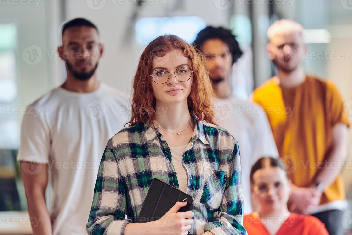 A diverse group of business people walking a corridor in the glass-enclosed office of a modern startup, including a person in a wheelchair and a woman wearing a hijab, showing a dynamic mix of photo