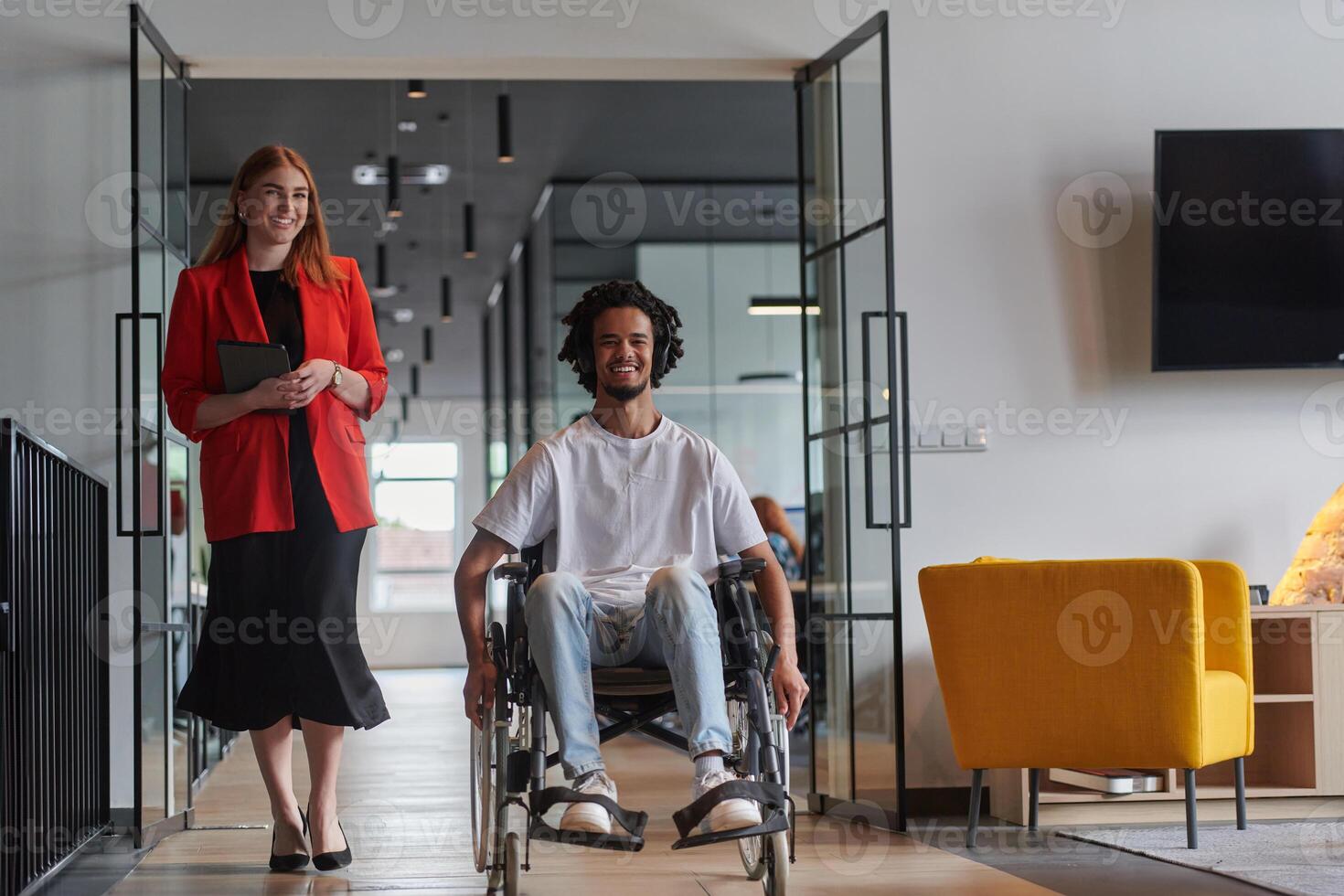 A group of young business people in a modern glass-walled office captures the essence of diversity and collaboration, while two colleagues, including an African American businessman in a wheelchair photo