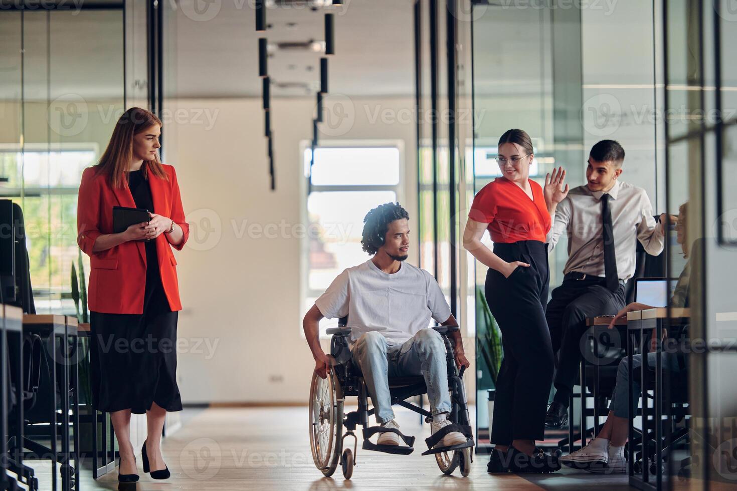 A group of young business people in a modern glass-walled office captures the essence of diversity and collaboration, while two colleagues, including an African American businessman in a wheelchair photo