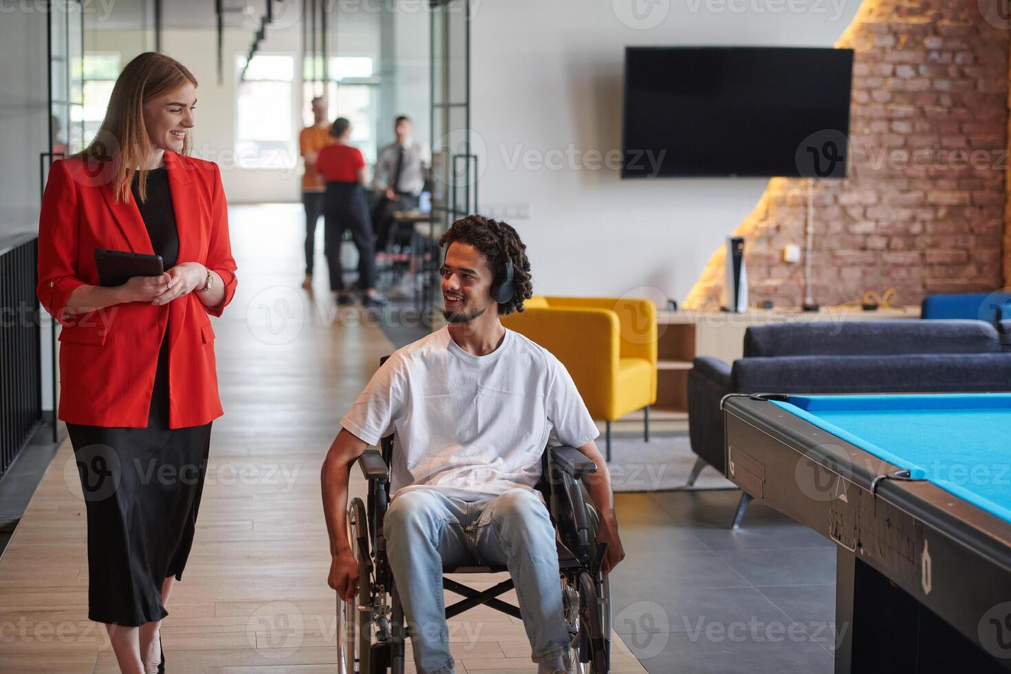 A group of young business people in a modern glass-walled office captures the essence of diversity and collaboration, while two colleagues, including an African American businessman in a wheelchair photo