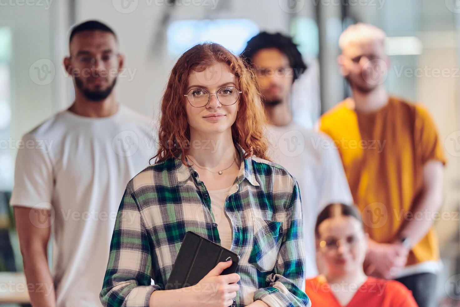 A diverse group of business people walking a corridor in the glass-enclosed office of a modern startup, including a person in a wheelchair and a woman wearing a hijab, showing a dynamic mix of photo