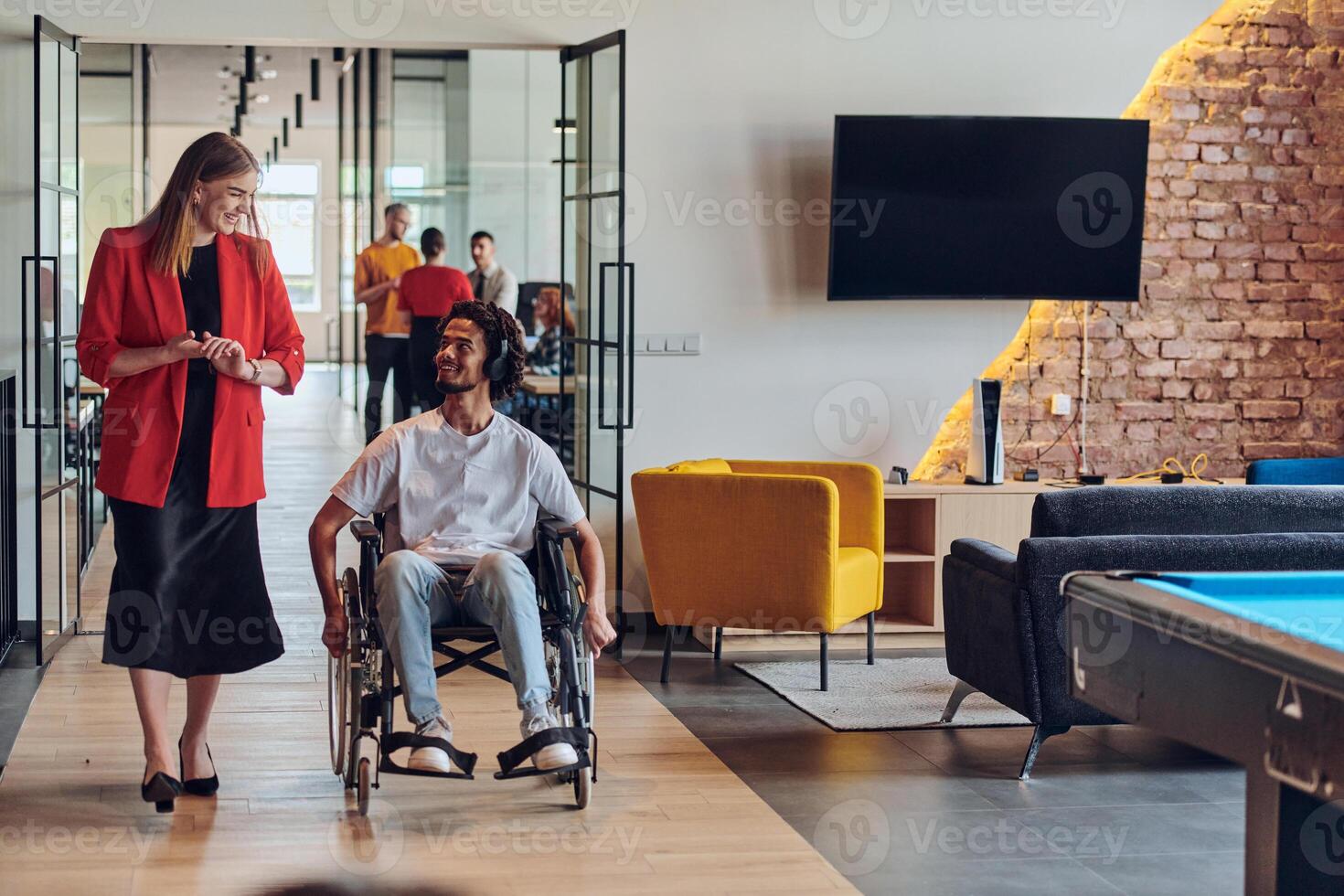 A group of young business people in a modern glass-walled office captures the essence of diversity and collaboration, while two colleagues, including an African American businessman in a wheelchair photo