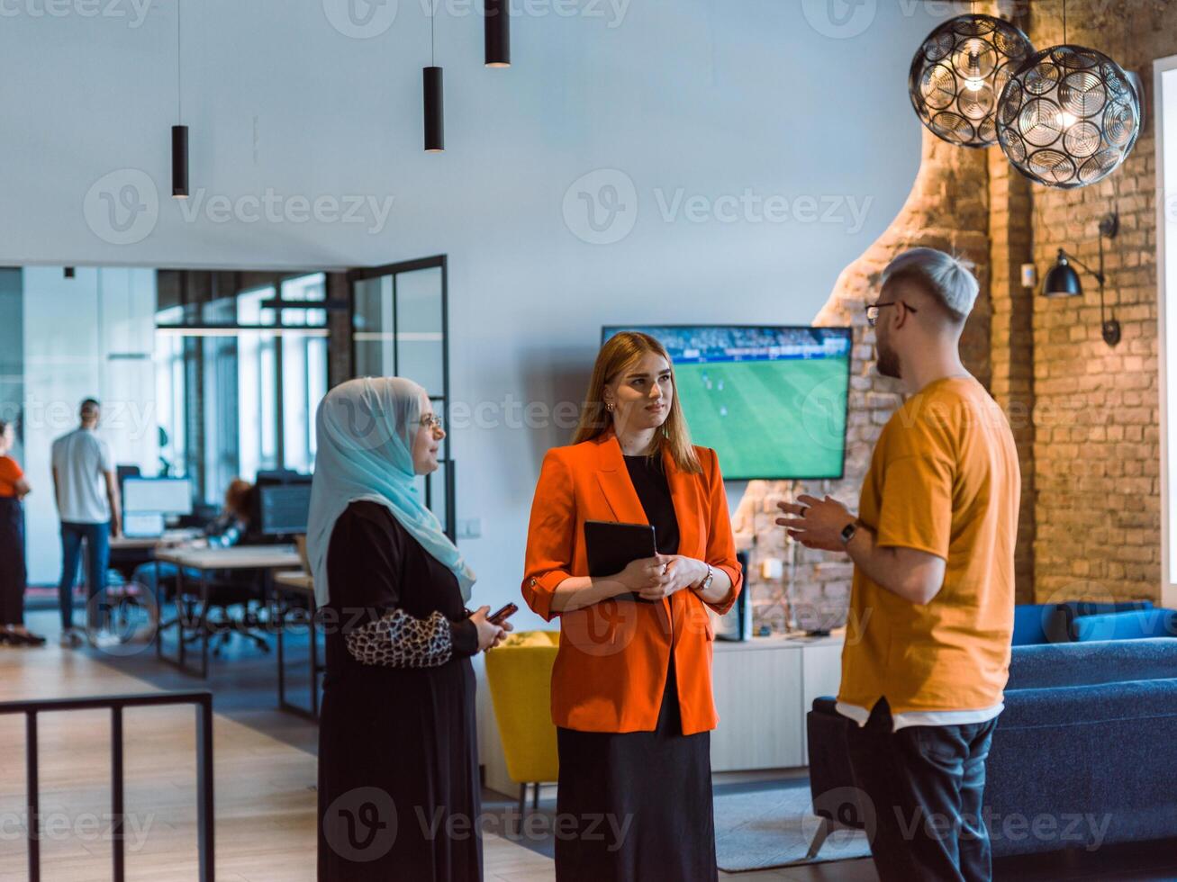 A group of young business colleagues, including a woman in a hijab, stands united in the modern corridor of a spacious startup coworking center, representing diversity and collaborative spirit photo