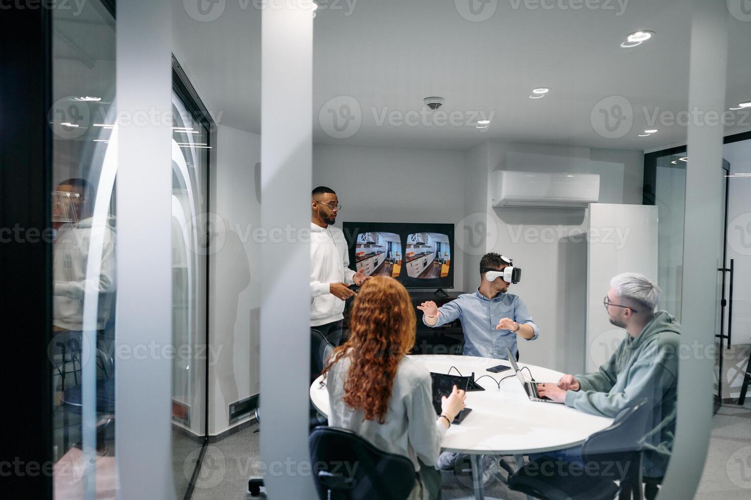 A diverse group of businessmen collaborates and tests a new virtual reality technology, wearing virtual glasses, showcasing innovation and creativity in their futuristic workspace photo