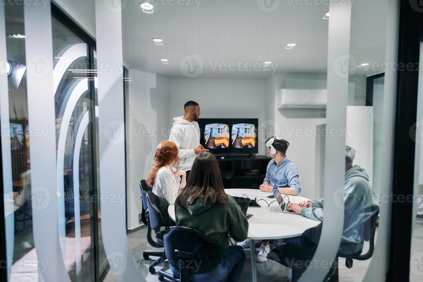 A diverse group of businessmen collaborates and tests a new virtual reality technology, wearing virtual glasses, showcasing innovation and creativity in their futuristic workspace photo