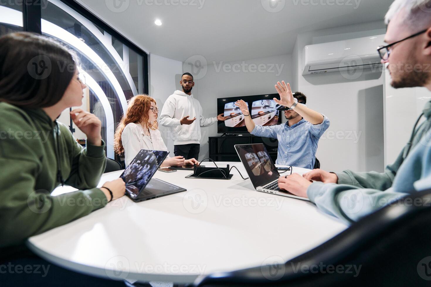 A diverse group of businessmen collaborates and tests a new virtual reality technology, wearing virtual glasses, showcasing innovation and creativity in their futuristic workspace photo