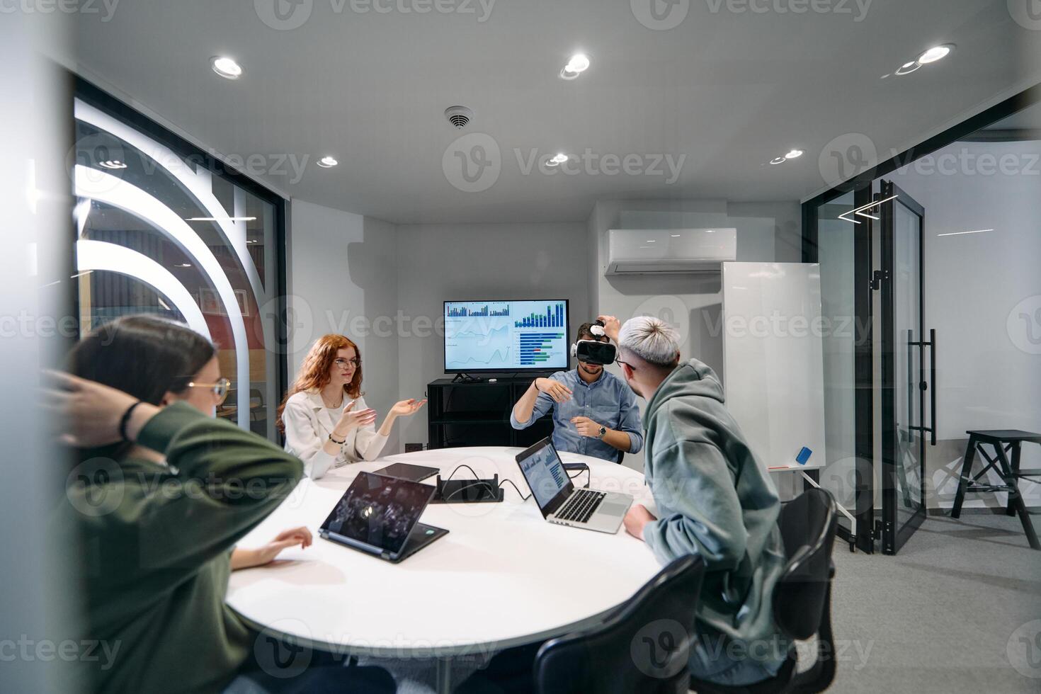 A diverse group of businessmen collaborates and tests a new virtual reality technology, wearing virtual glasses, showcasing innovation and creativity in their futuristic workspace photo