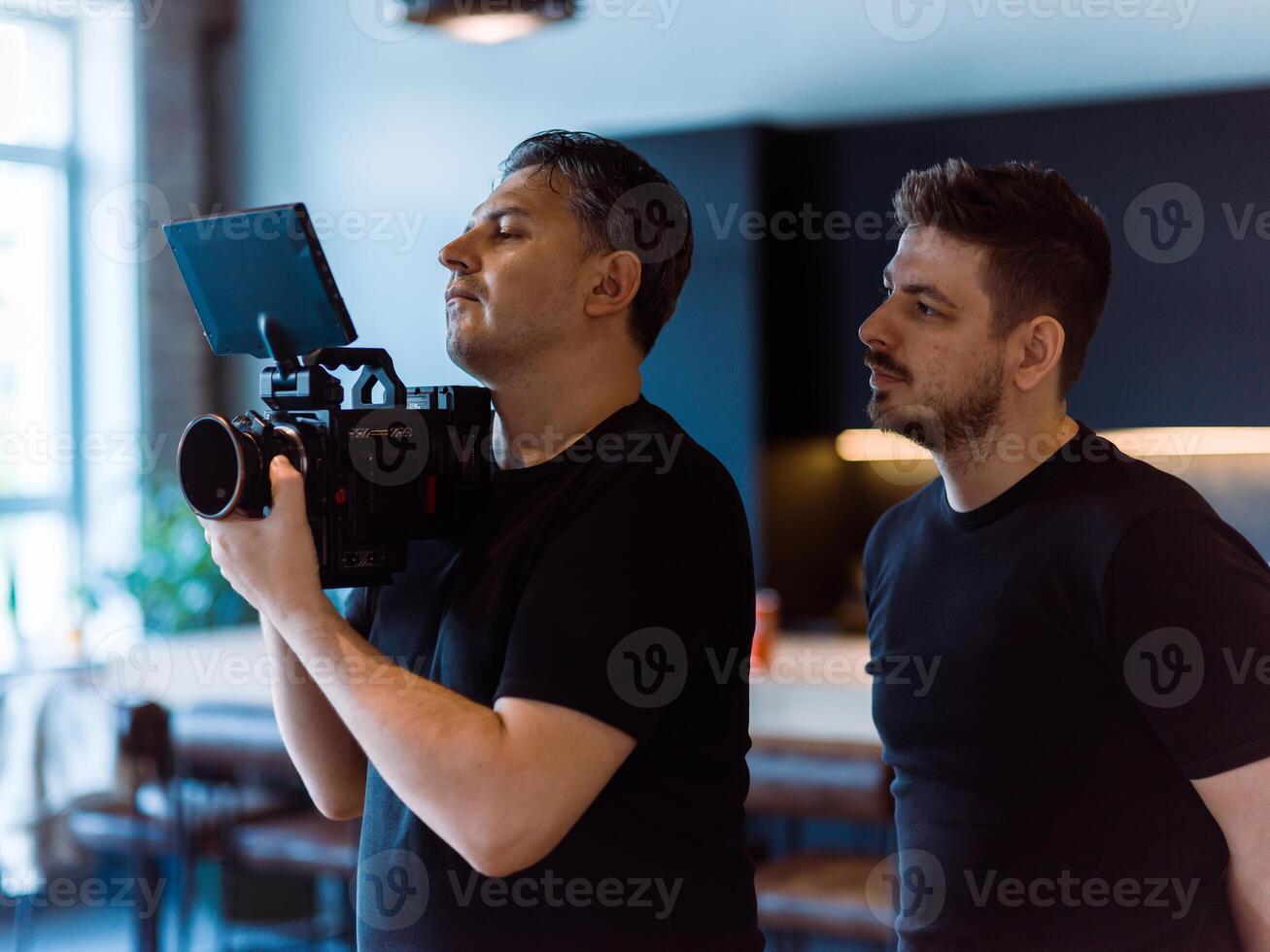 Director of photography with a camera in his hands on the set. Professional videographer at work on filming a movie, commercial or TV series. Filming process indoors, studio photo