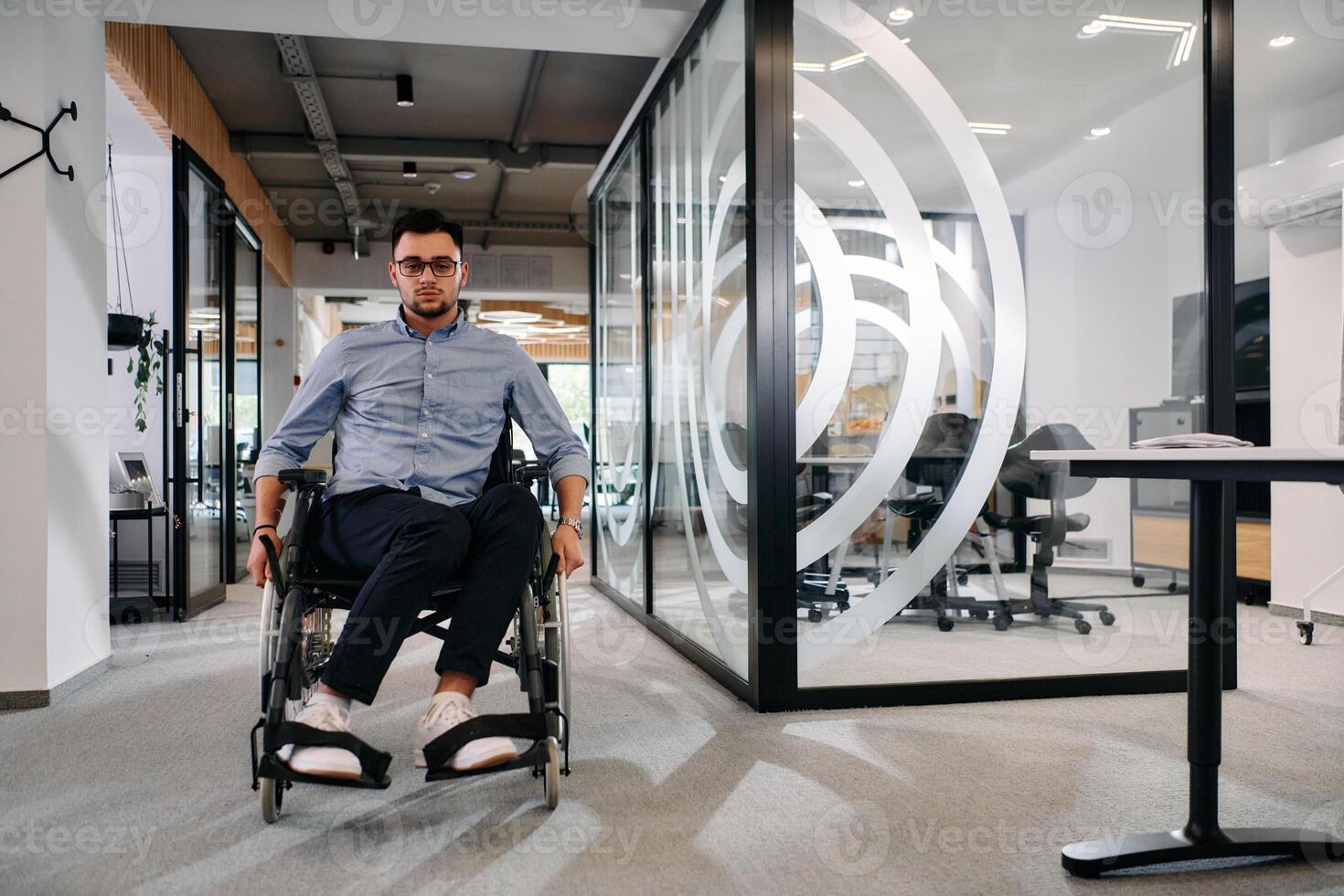 In a large modern corporation, a determined businessman in a wheelchair navigates through a hallway, embodying empowerment and inclusivity in the corporate world. photo