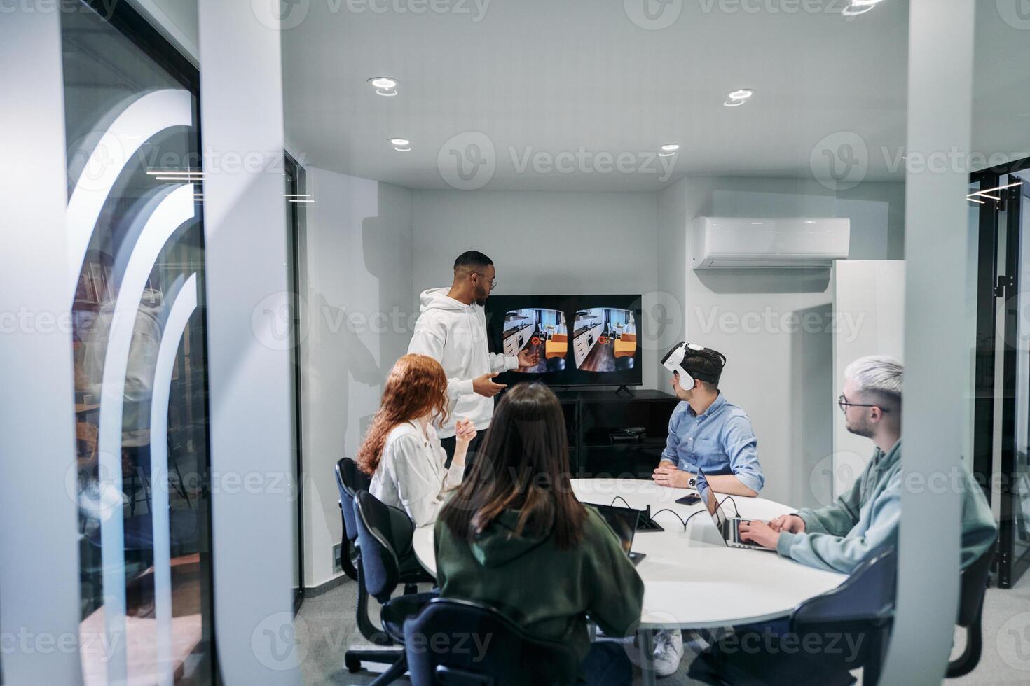 A diverse group of businessmen collaborates and tests a new virtual reality technology, wearing virtual glasses, showcasing innovation and creativity in their futuristic workspace photo