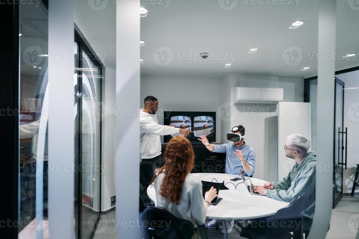 A diverse group of businessmen collaborates and tests a new virtual reality technology, wearing virtual glasses, showcasing innovation and creativity in their futuristic workspace photo