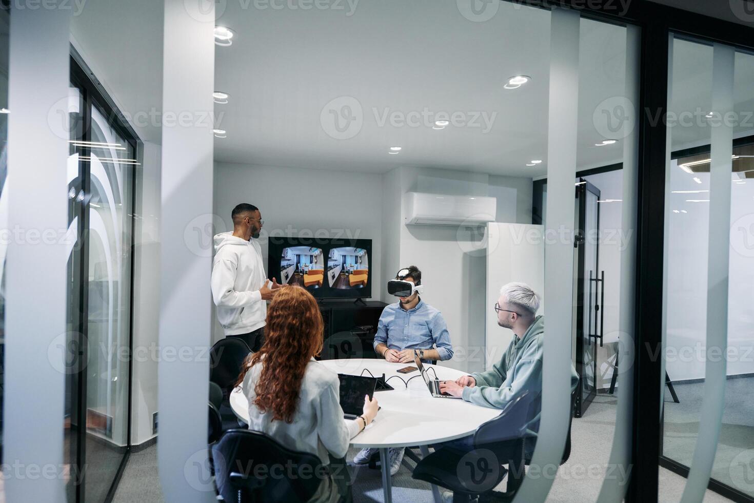 A diverse group of businessmen collaborates and tests a new virtual reality technology, wearing virtual glasses, showcasing innovation and creativity in their futuristic workspace photo