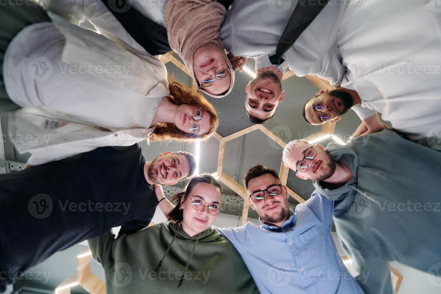 In a modern office, a group of young business professionals is captured in a warm and embracing hug, reflecting the spirit of unity, collaboration, and shared success in their dynamic workplace. photo