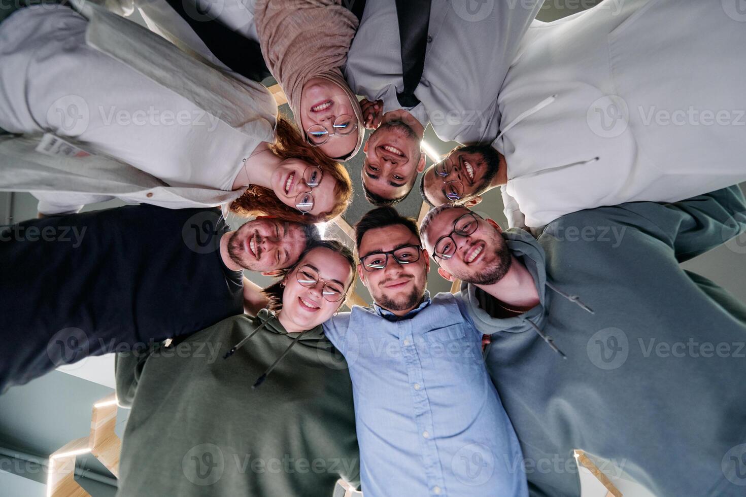 In a modern office, a group of young business professionals is captured in a warm and embracing hug, reflecting the spirit of unity, collaboration, and shared success in their dynamic workplace. photo