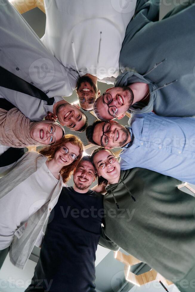 In a modern office, a group of young business professionals is captured in a warm and embracing hug, reflecting the spirit of unity, collaboration, and shared success in their dynamic workplace. photo