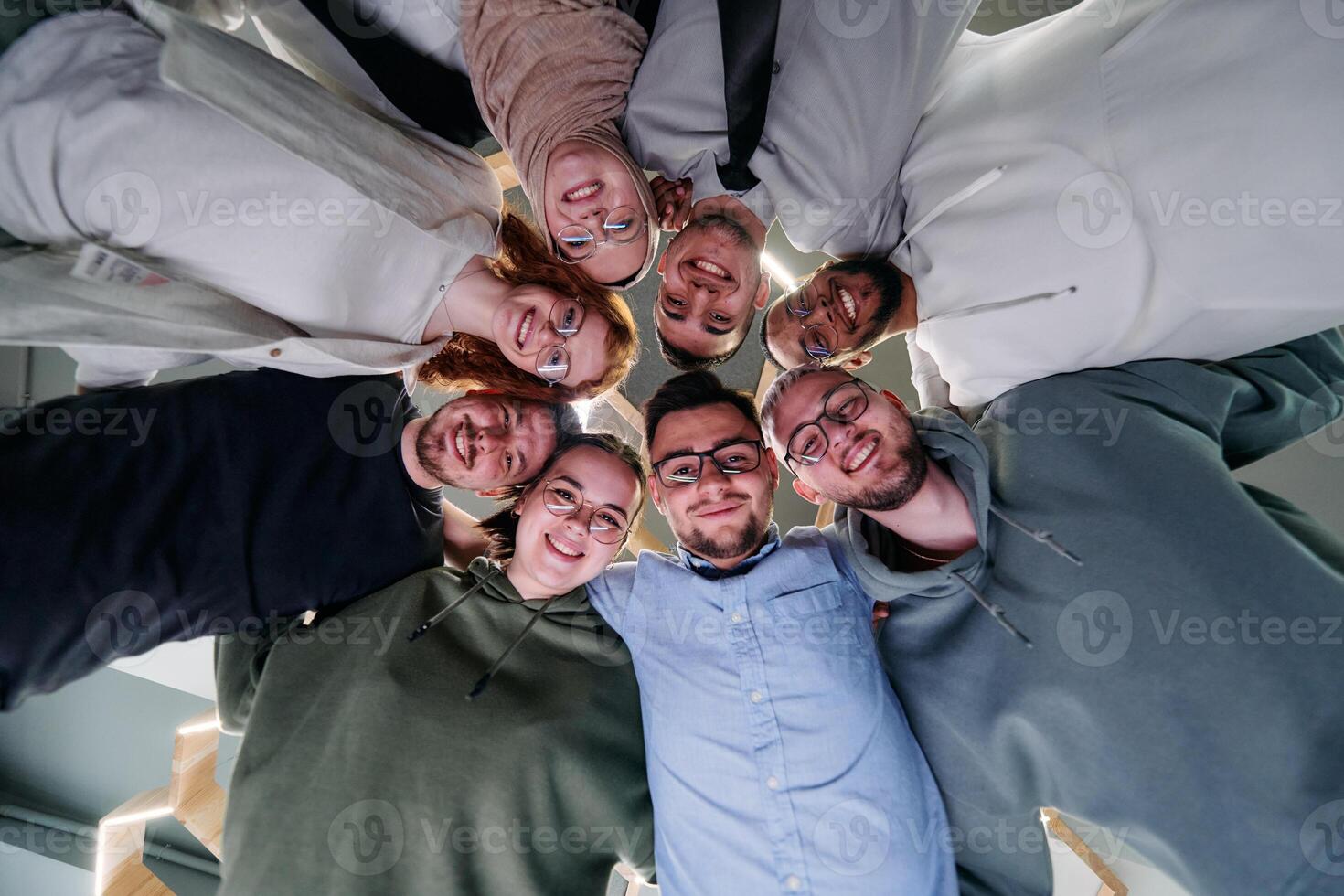 In a modern office, a group of young business professionals is captured in a warm and embracing hug, reflecting the spirit of unity, collaboration, and shared success in their dynamic workplace. photo