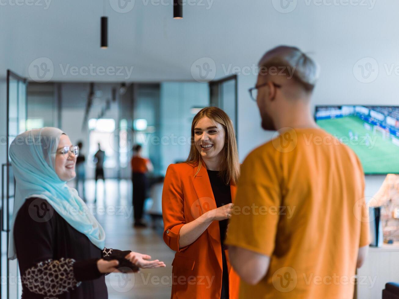 A group of young business colleagues, including a woman in a hijab, stands united in the modern corridor of a spacious startup coworking center, representing diversity and collaborative spirit photo