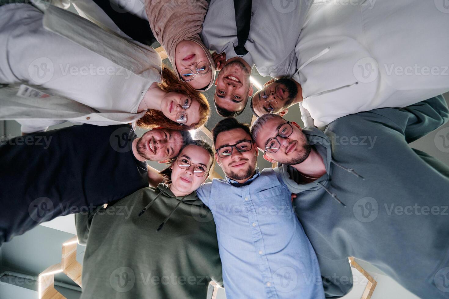 In a modern office, a group of young business professionals is captured in a warm and embracing hug, reflecting the spirit of unity, collaboration, and shared success in their dynamic workplace. photo