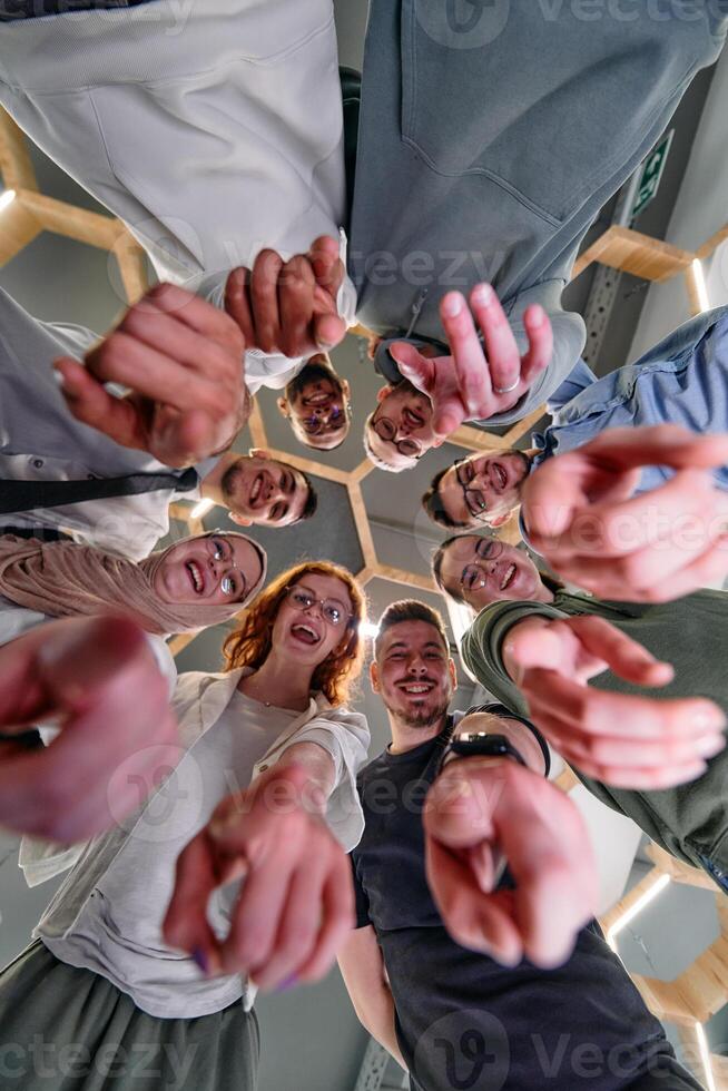 A group of cheerful young people gathered in a circle, pointing at the camera from a low-angle perspective. photo