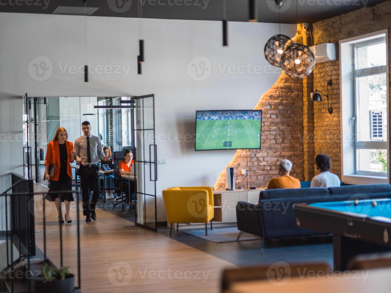 A business group, including an African American businessman in a wheelchair, collaborates within a modern glass office, actively engaged around a computer and laptop, collectively solving diverse photo
