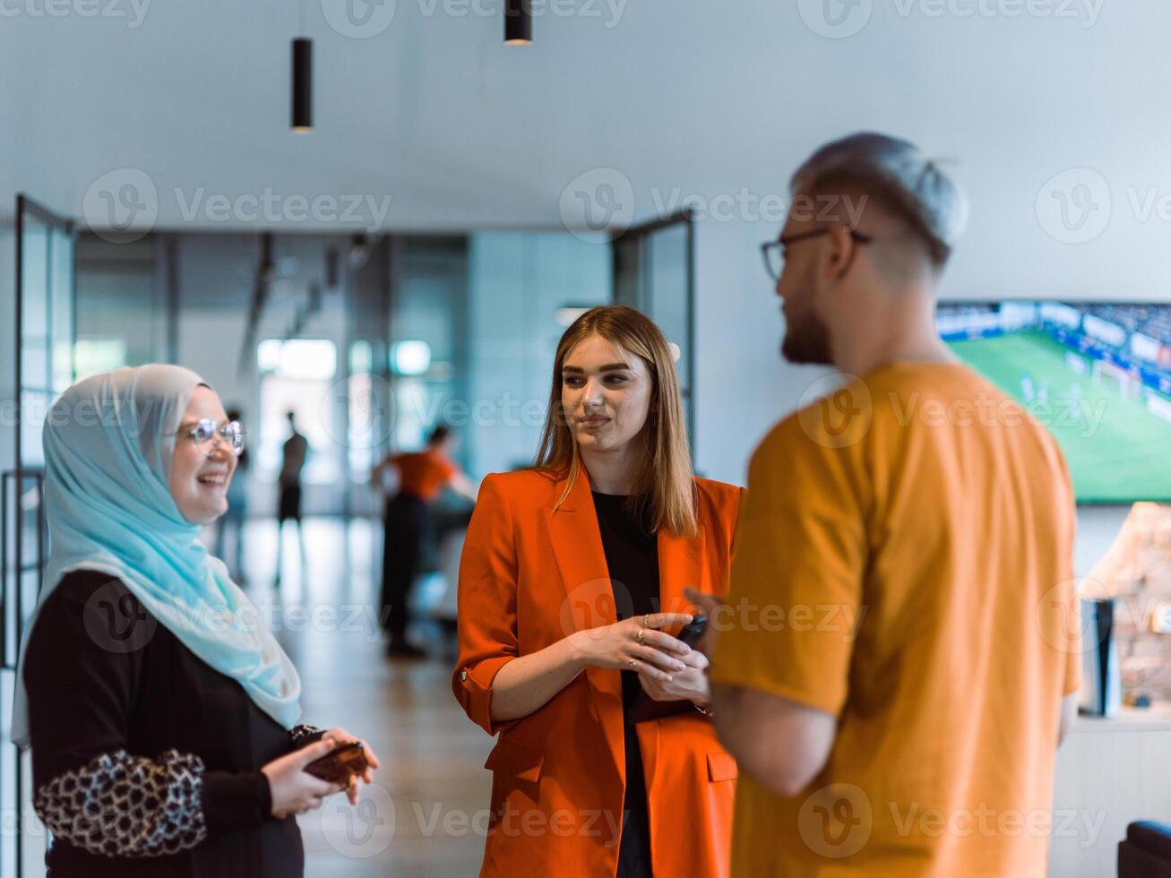 A group of young business colleagues, including a woman in a hijab, stands united in the modern corridor of a spacious startup coworking center, representing diversity and collaborative spirit photo