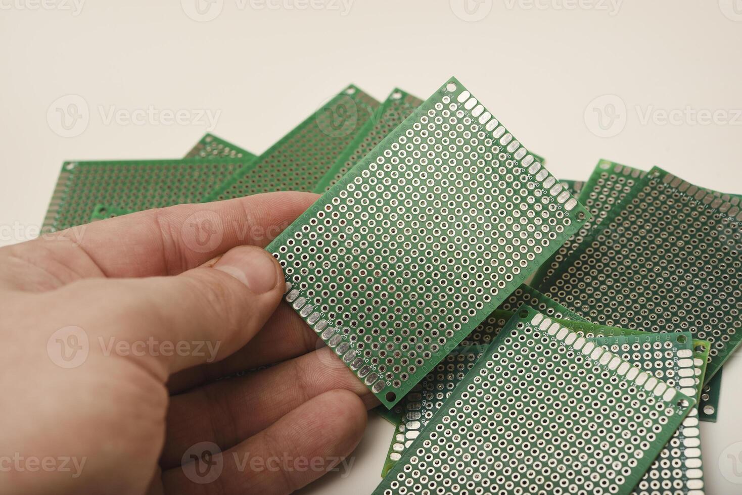 The printed circuit board is in your hand. A green breadboard for electronics. photo