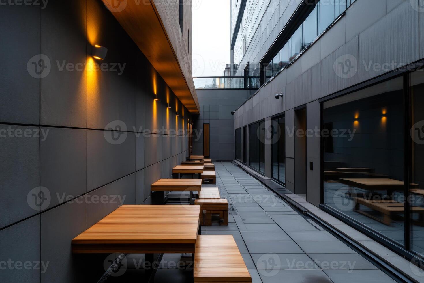 Modern outdoor seating area with wooden tables and ambient lighting in an urban setting during twilight photo