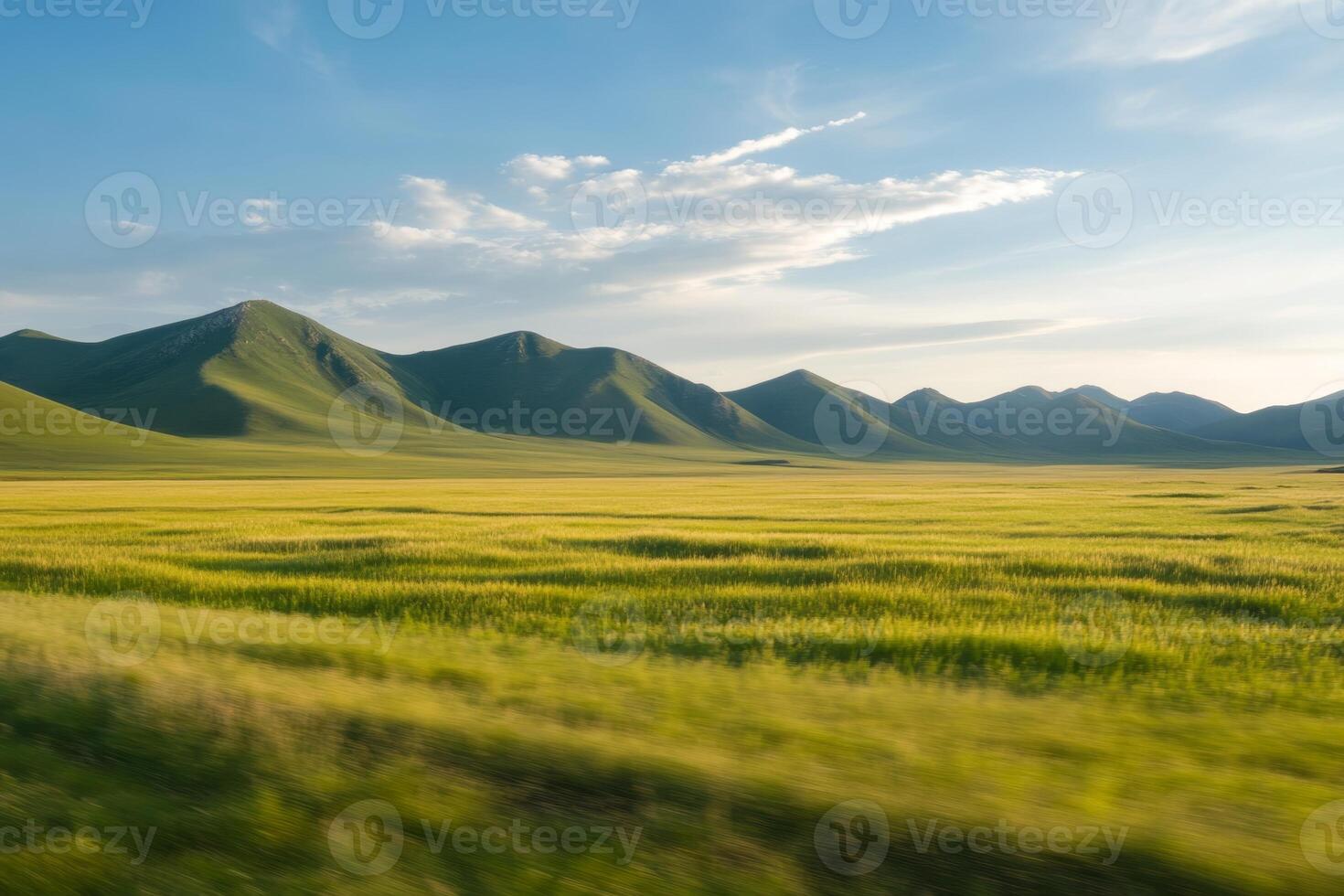 Expansive green fields and rolling hills under a clear blue sky at sunset photo