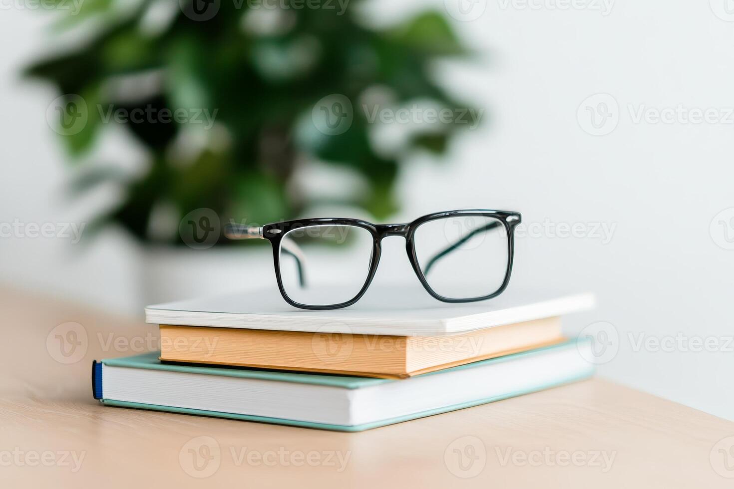 Glasses resting on stacked books with greenery in the background during a calm indoor setting photo