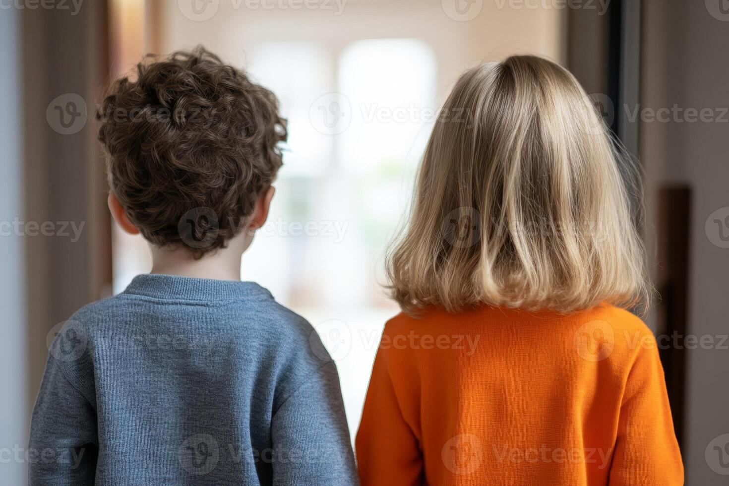 Children standing together in a brightly lit hallway while looking towards an open space outside photo