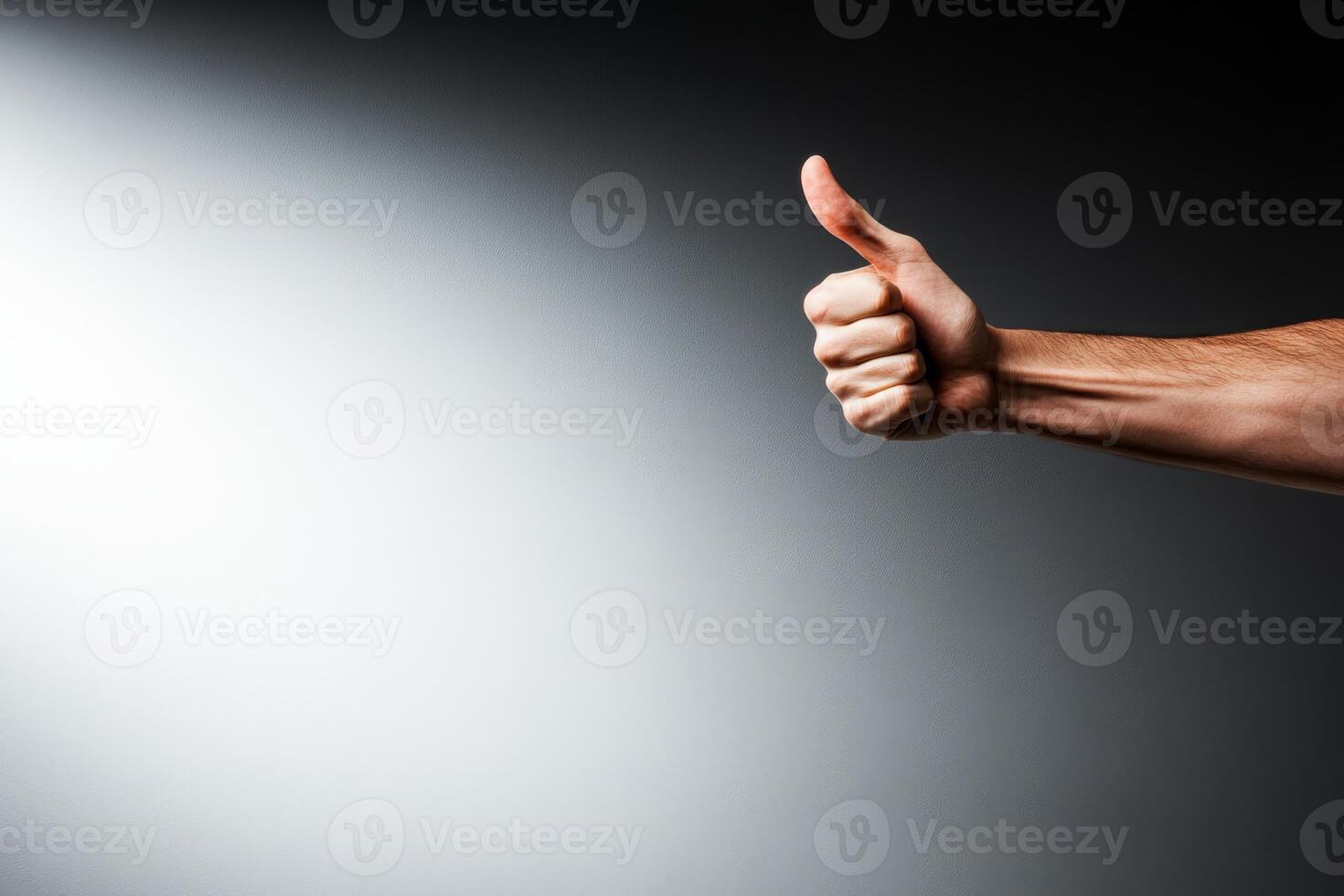 Hand giving a thumbs up gesture against a simple background in a well-lit setting photo