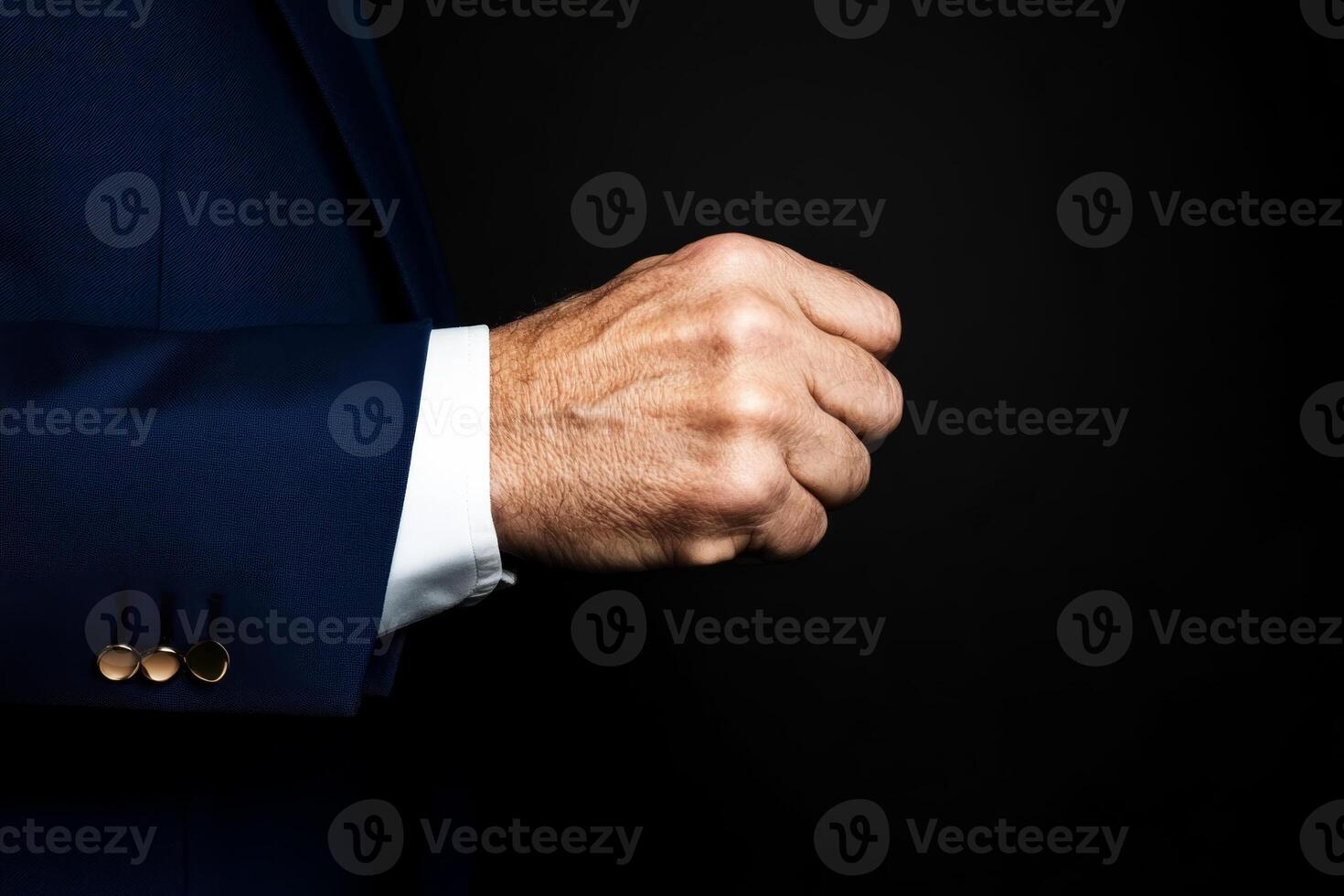 Professional man in blue suit making a fist against a dark background to convey determination and strength in a business setting photo