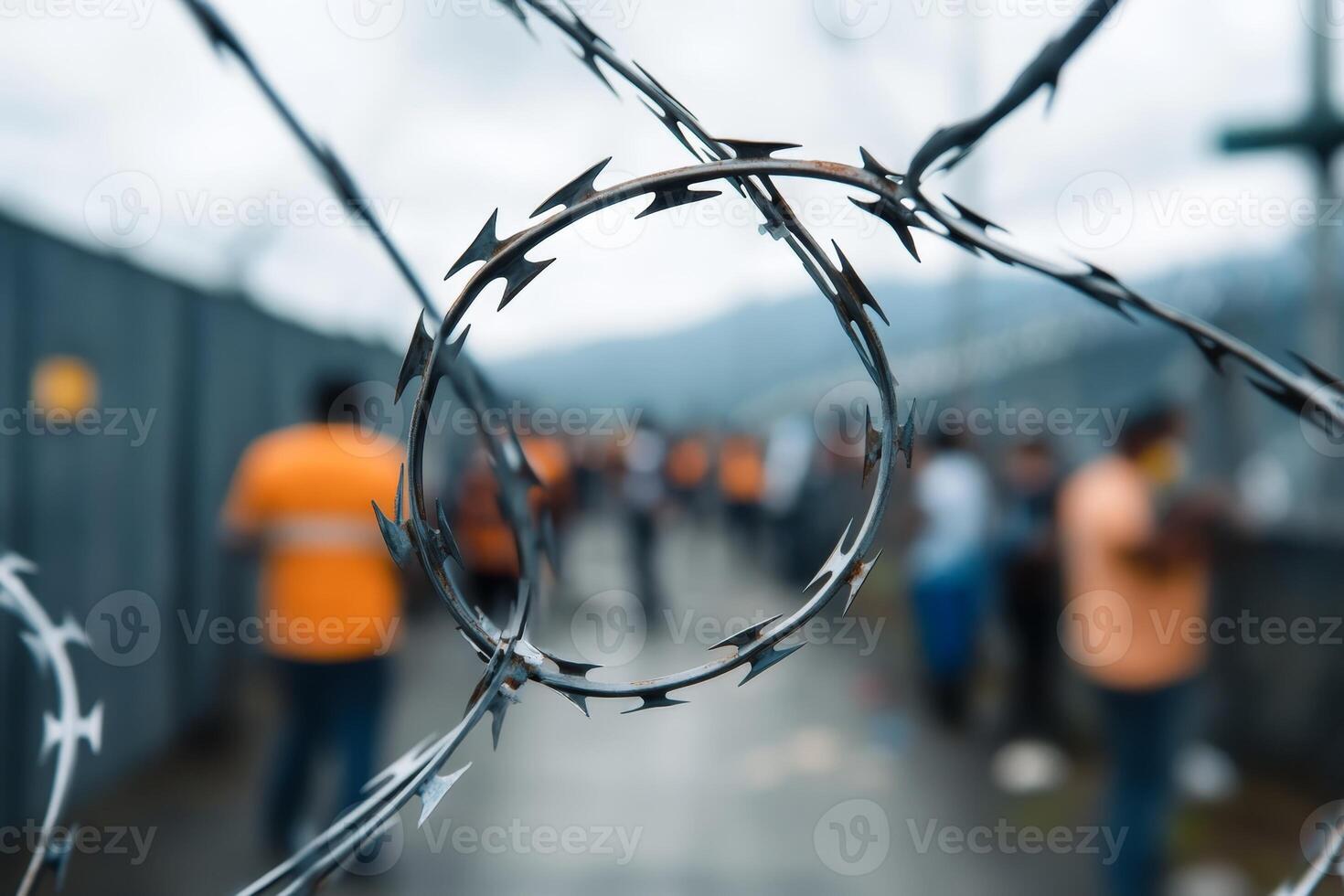 Workers gathered behind barbed wire at a construction site under cloudy skies photo