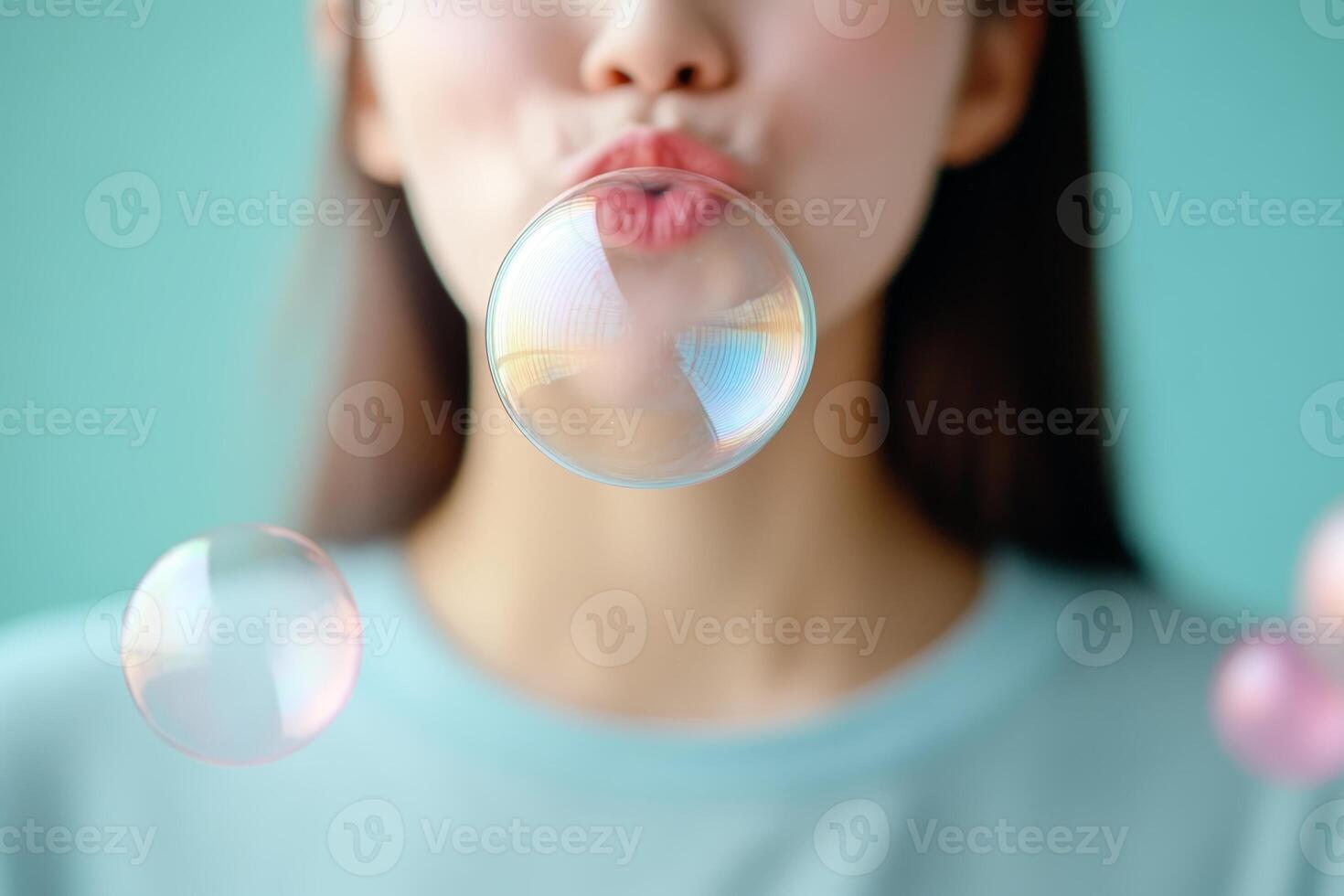 Girl blowing soap bubbles in a colorful and playful setting with a light blue background photo