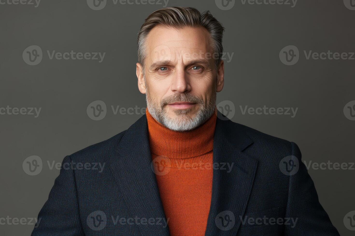 Mature man in stylish attire poses confidently against simple gray backdrop showcasing timeless fashion statement photo