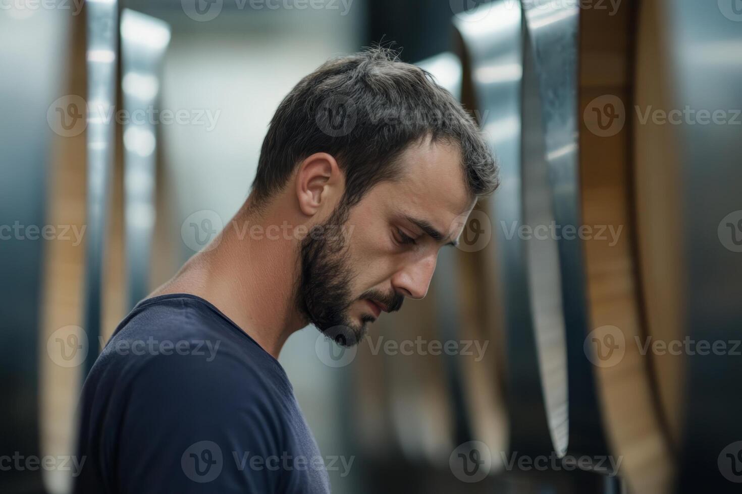 Thoughtful male winemaker standing in cellar with wine barrels photo