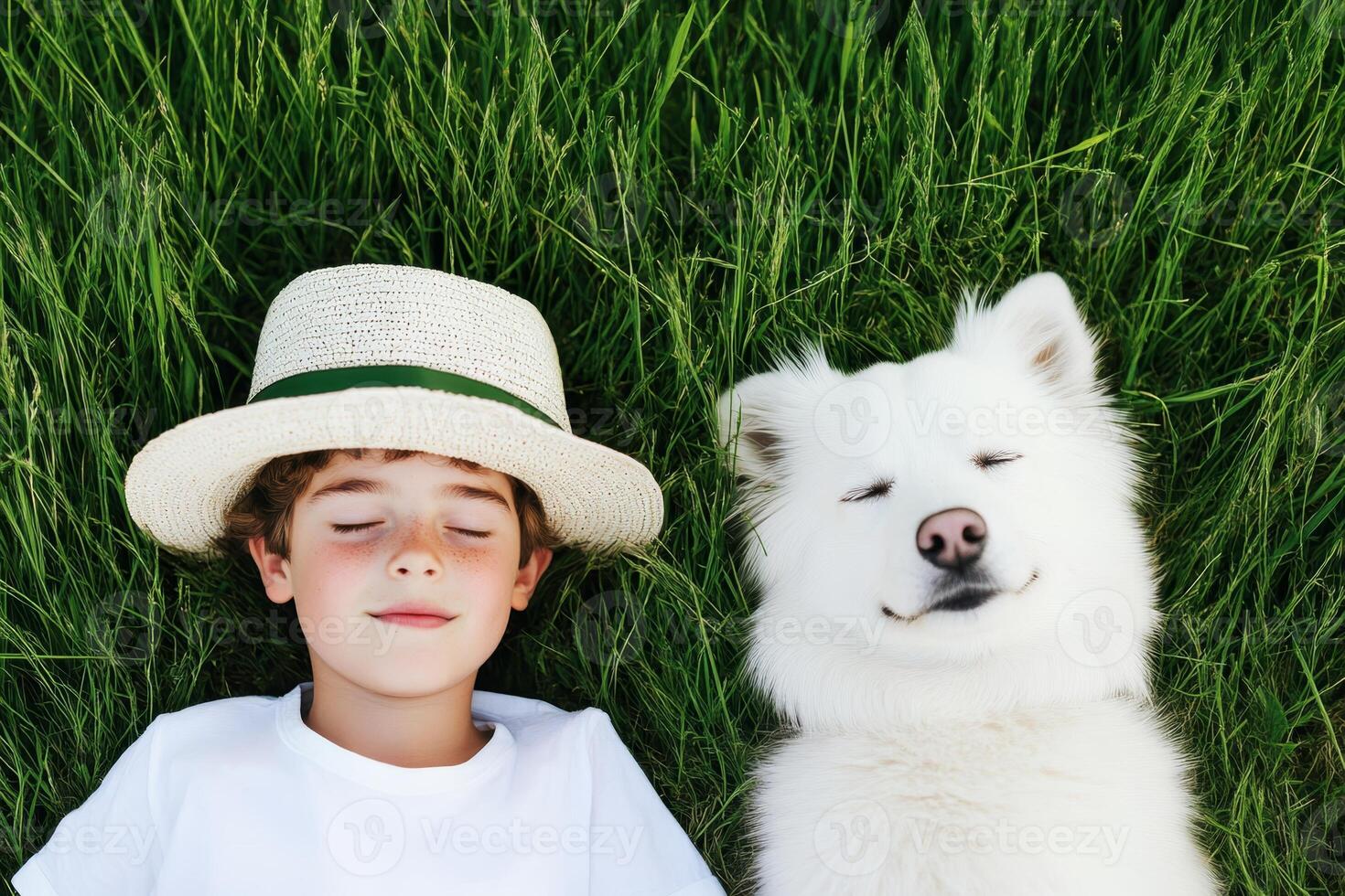 Boy enjoys a sunny afternoon while lying in grass next to smiling dog on a warm day photo