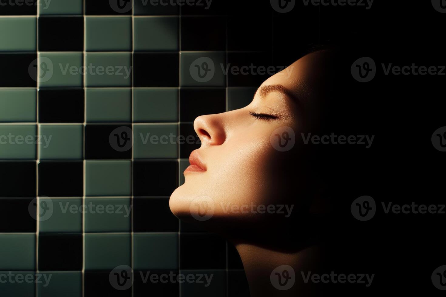 Woman's serene profile illuminated against dark tiled background in a tranquil indoor setting during evening light photo