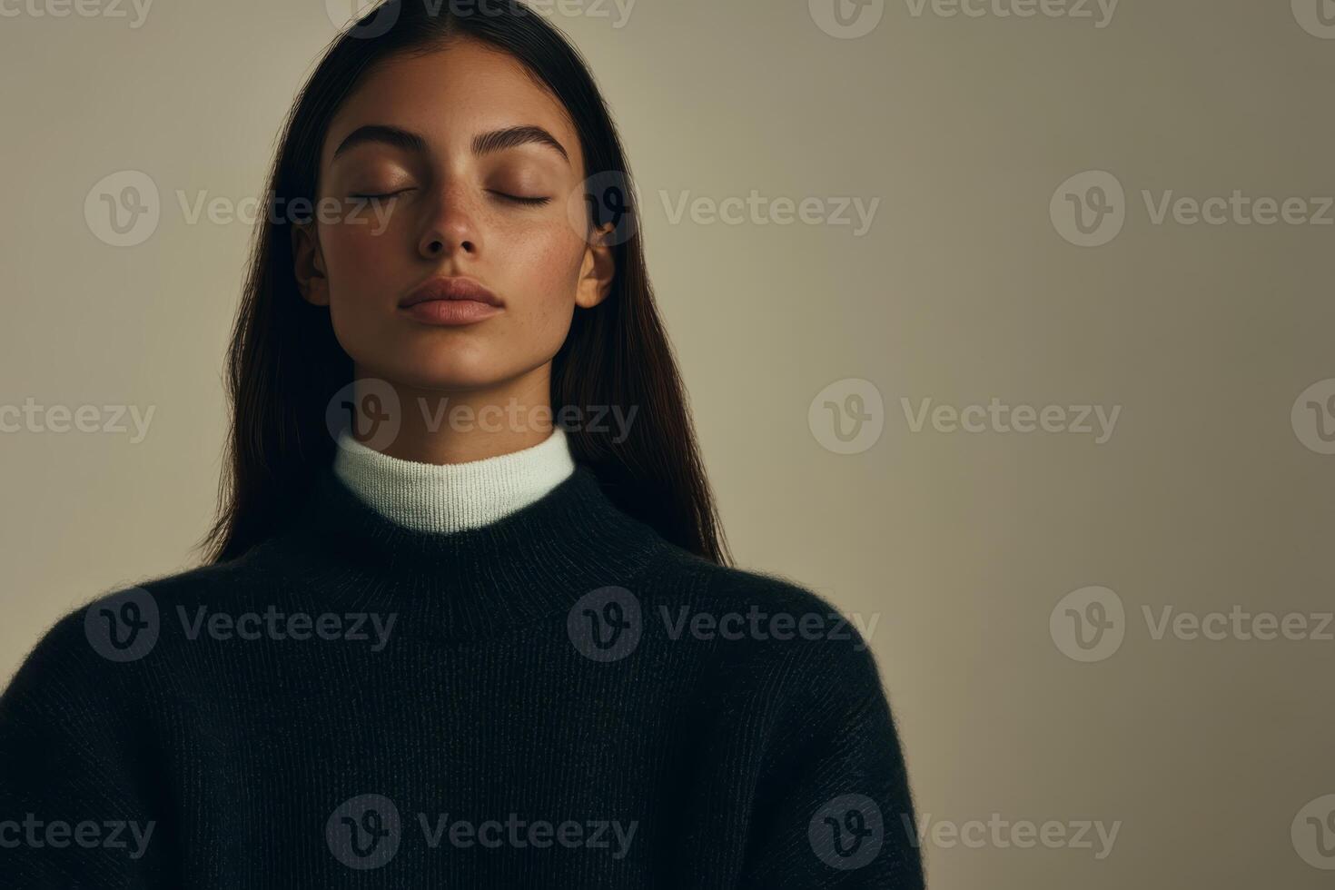 Woman in a cozy sweater poses with serene expression against a neutral background photo