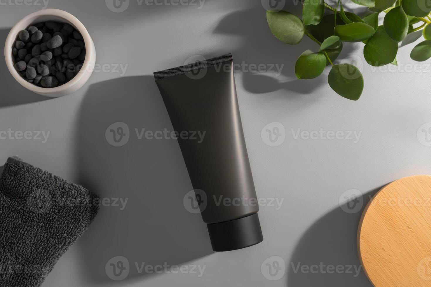 Black tube of skincare product placed on a gray surface with stones and plants in a serene spa setting photo