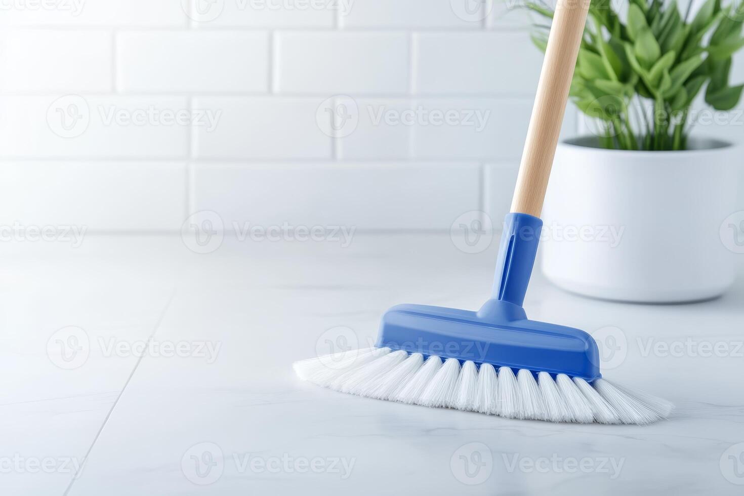 Clean white floor with a blue broom next to a potted plant in a bright indoor setting during daylight hours photo
