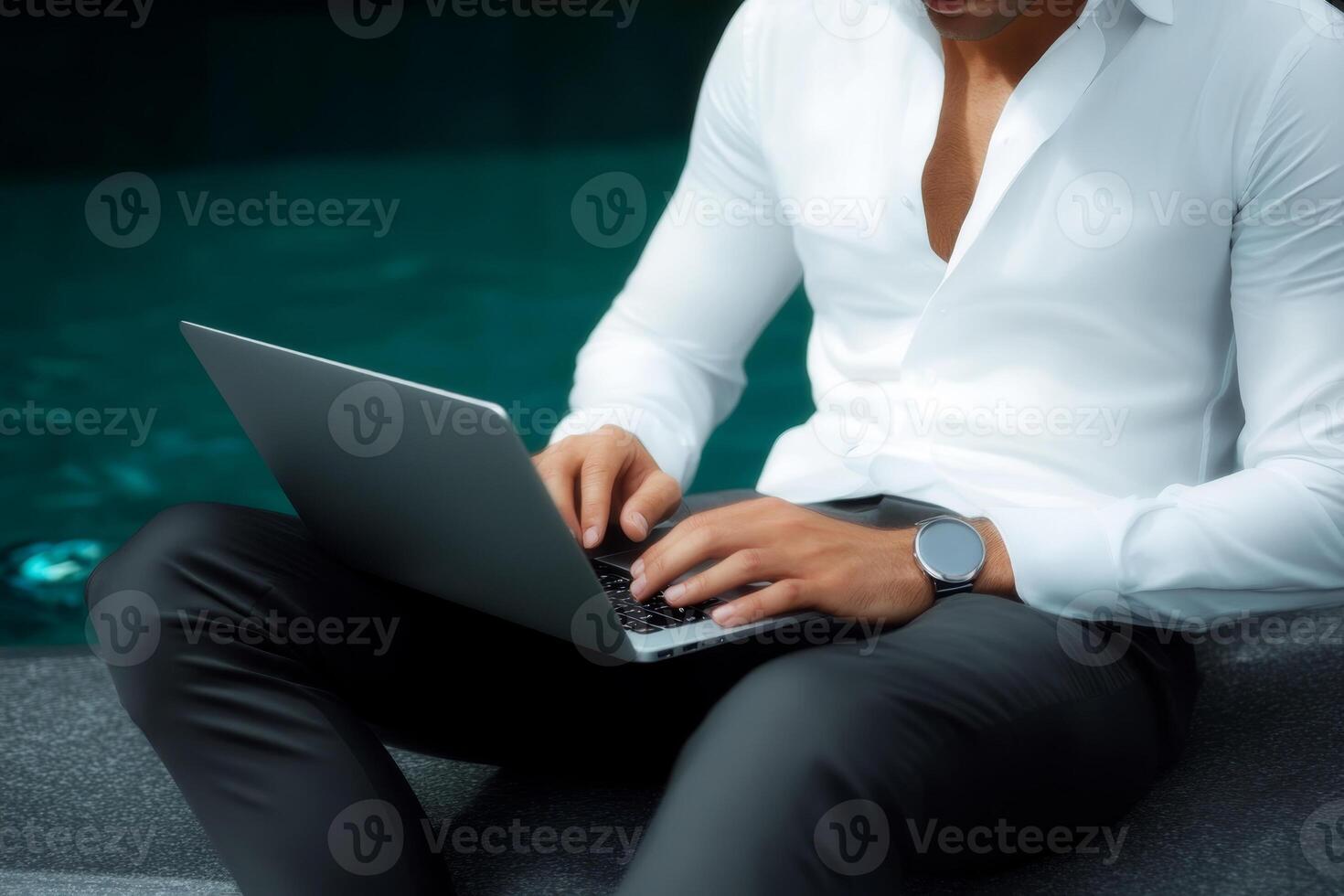 Professional man working on a laptop by a tranquil poolside during a sunny day photo