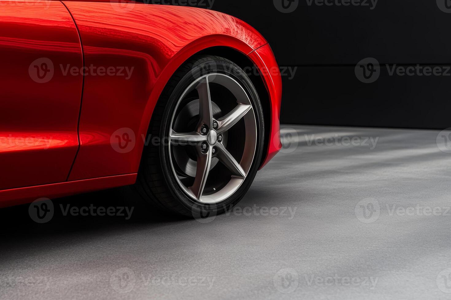 Red sports car parked on a modern surface with shadows highlighting its sleek lines and alloy wheels photo