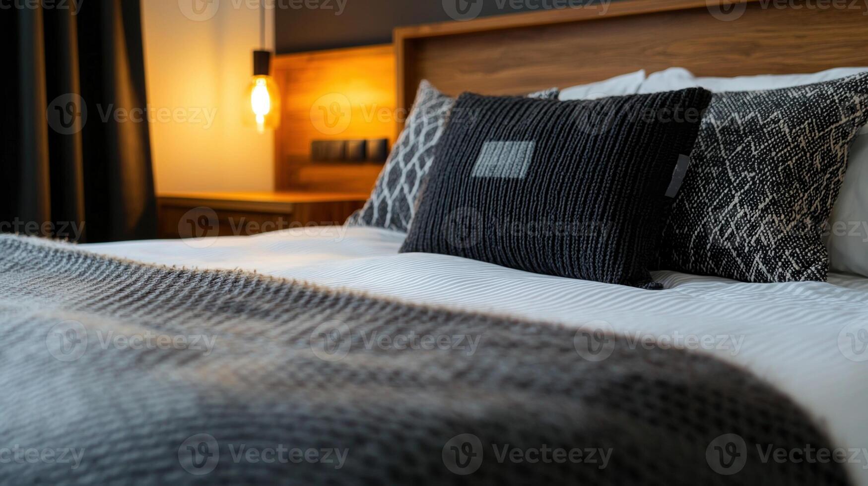 A bed with a black pillow and a gray blanket photo