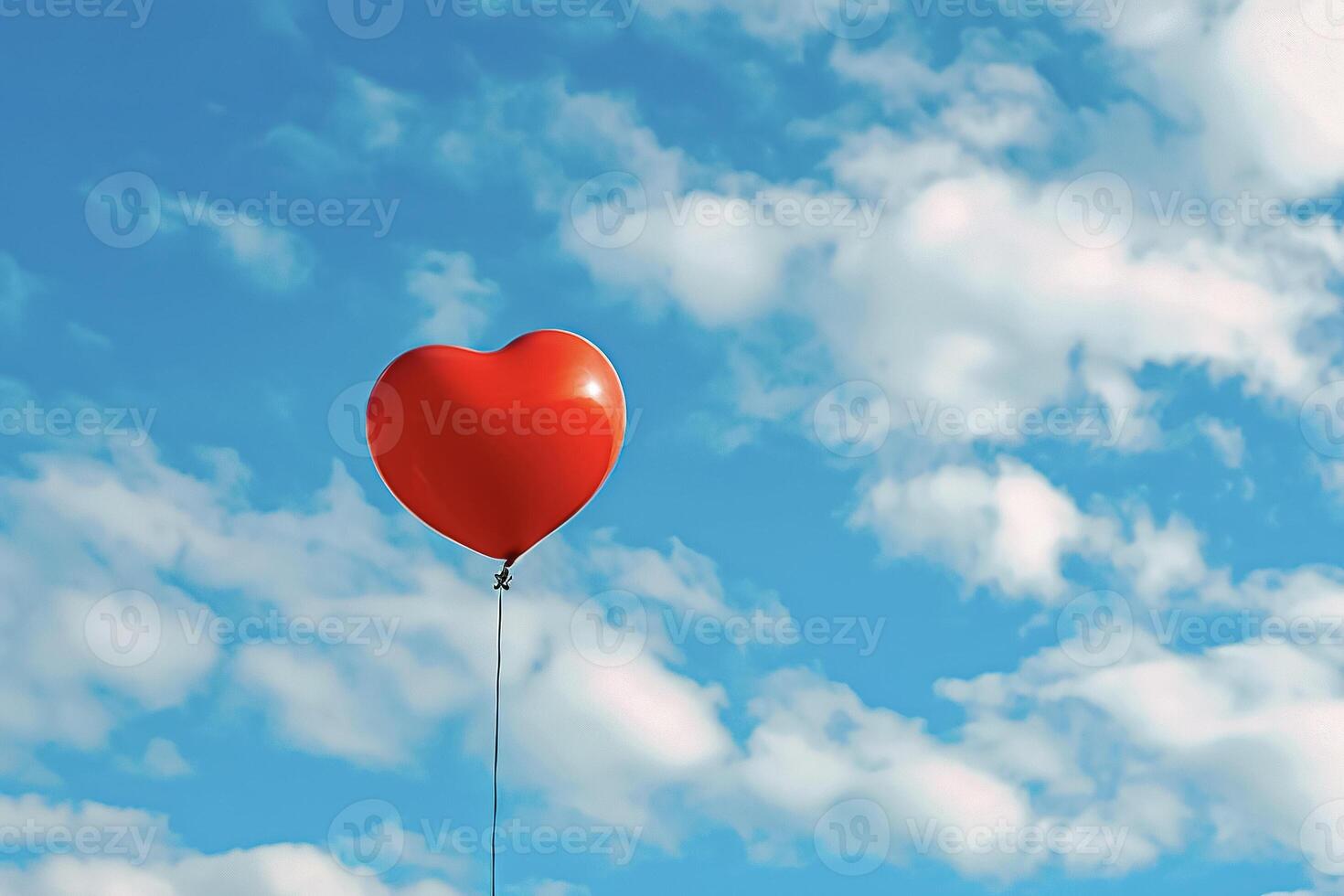 A red heart shaped balloon floating in the sky photo