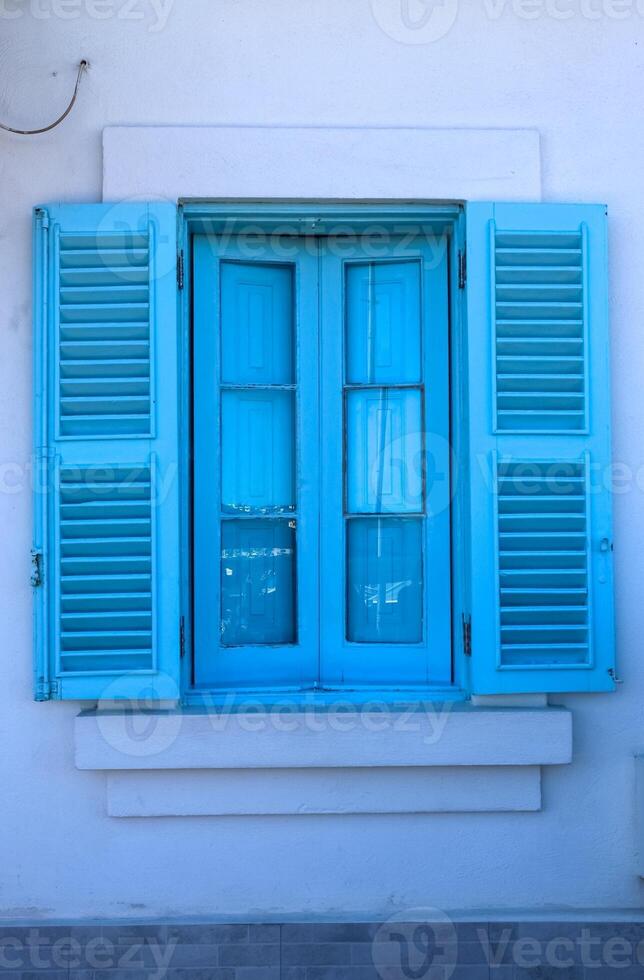 Bright blue window with open shutters illuminating white wall photo