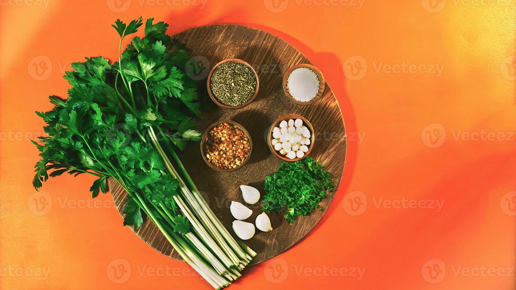 Fresh parsley, garlic, and assorted spices in wooden bowls on a rustic wooden plate against an orange background, perfect for food blogs, healthy eating promotions, or vibrant recipe visuals. photo