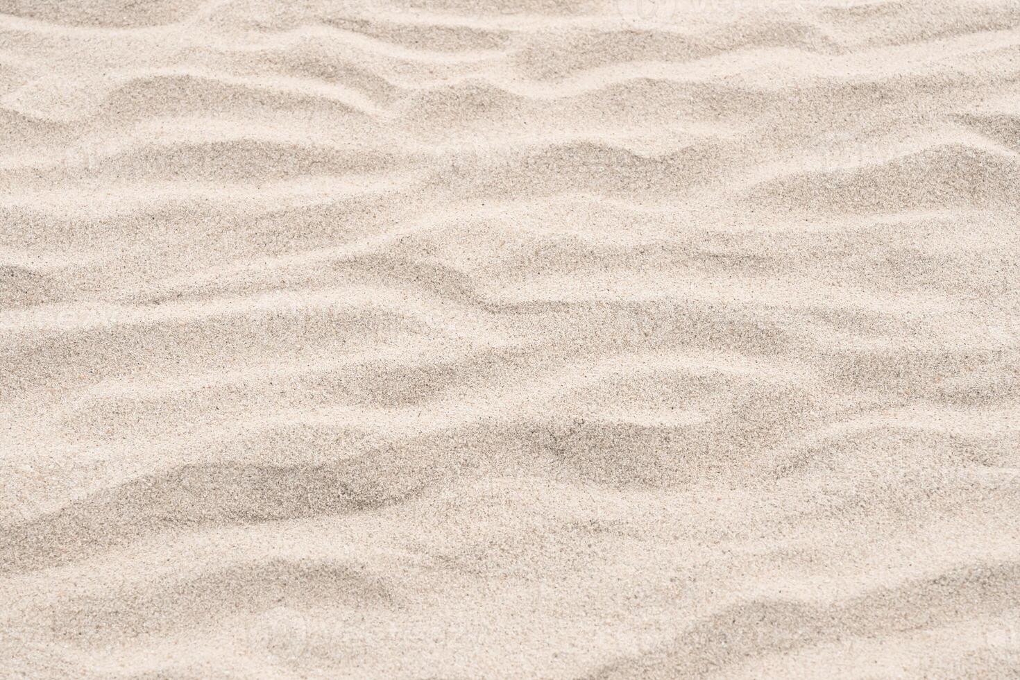 Sand beach texture background by the sea,Sand dunes floor with waves pattern for summer vacation travel banner,Nature landscape desert brown sand with light, shadow.Top view natural yellow grain sand photo
