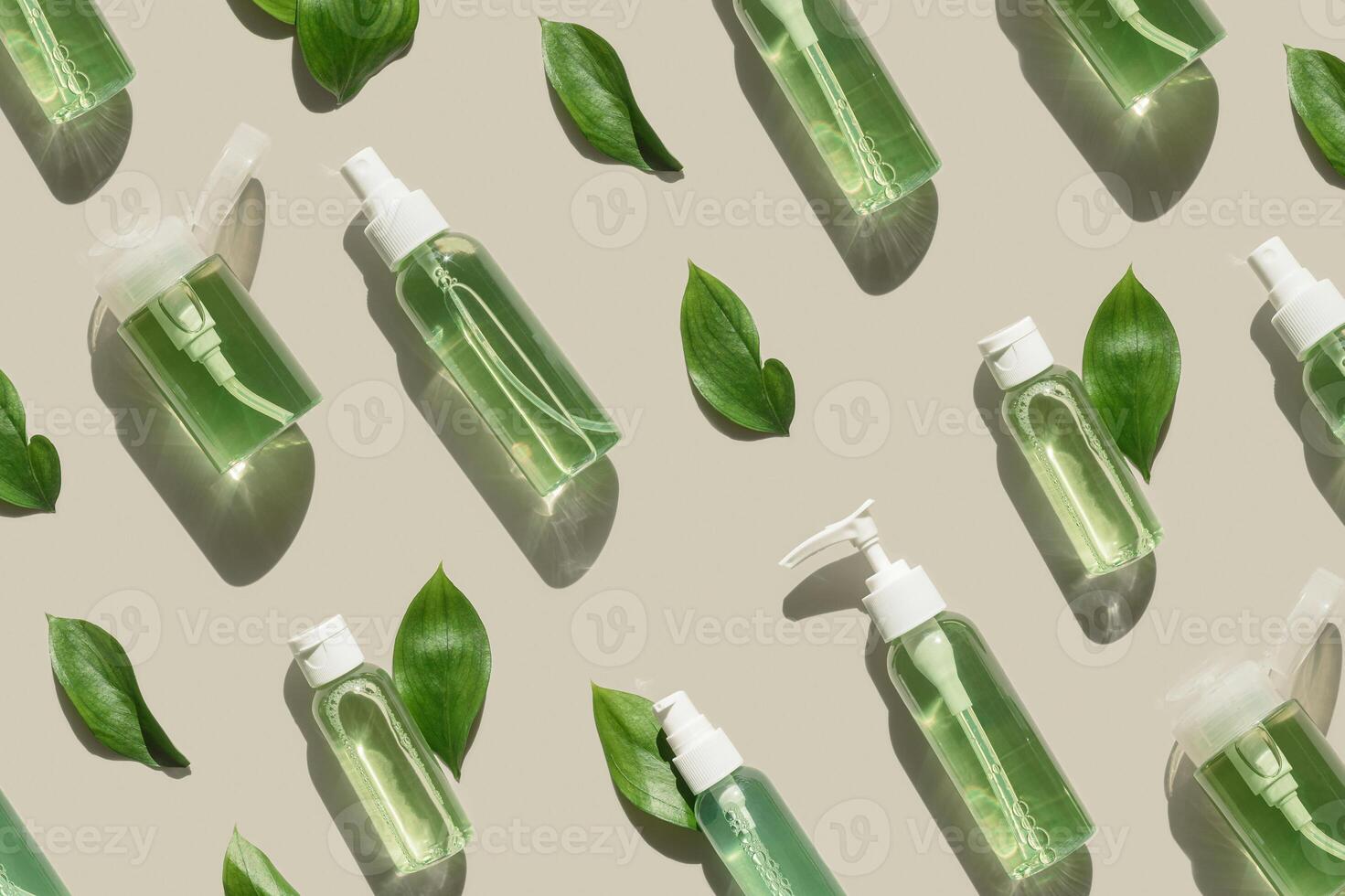 Natural Organic Cosmetic products with green liquid and leaves for skin treatment, beauty routine, skin health. Minimal top view pattern with lotion, tonic, gel, micellar water mockup with shadows photo